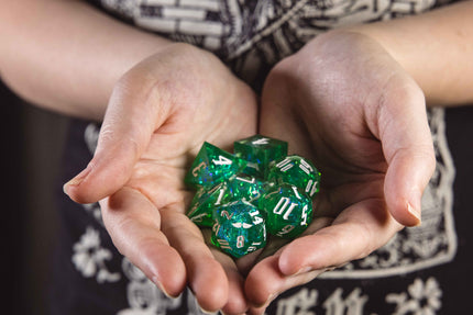 Two hands holding a set of seven green and white dice