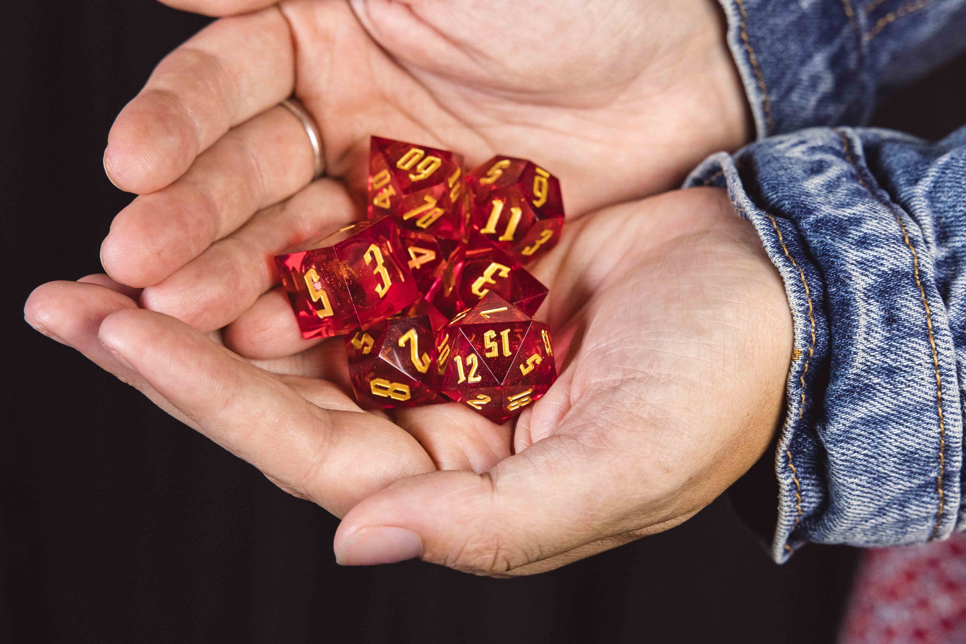 Two hands holding a set of red glittery dice with yellow numbering