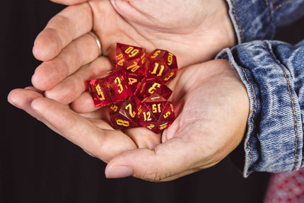 Two hands holding a set of red glittery dice with yellow numbering