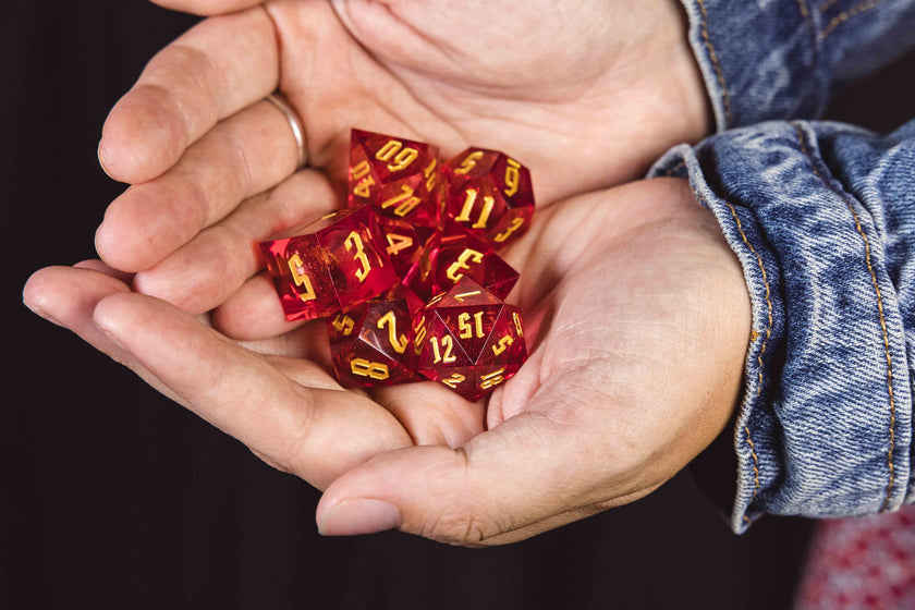 Two hands holding a set of red glittery dice with yellow numbering
