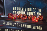 Red polyhedral dice set on top of a book titled 'Soliloquy of Annihilation'.