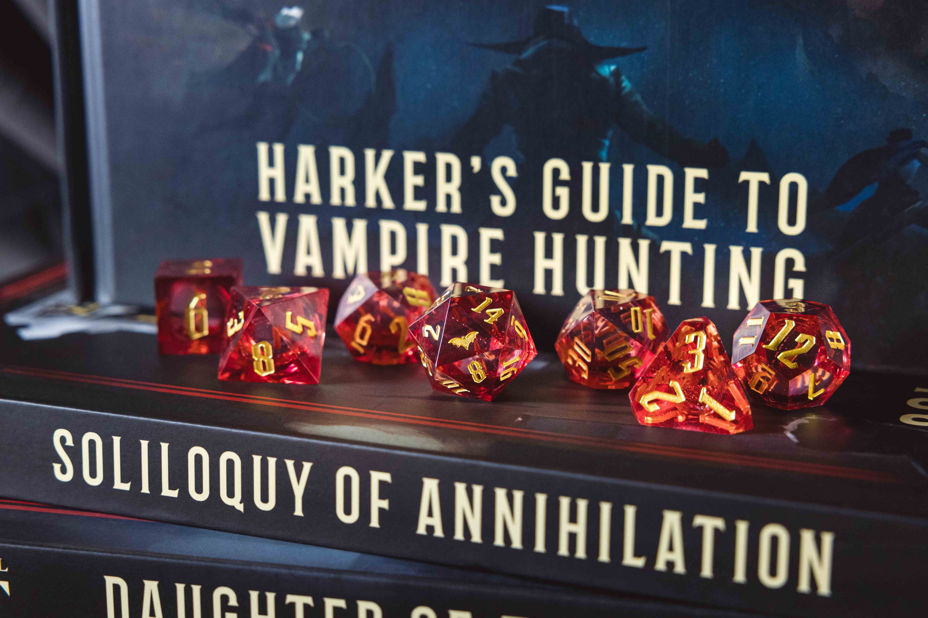 Red polyhedral dice set on top of a book titled 'Soliloquy of Annihilation'.