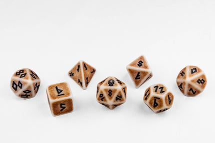Set of seven polyhedral dice in ivory and aged brown with black numbering on a white background.