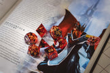 Set of red and metallic gold flake polyhedral dice on a TTRPG book page